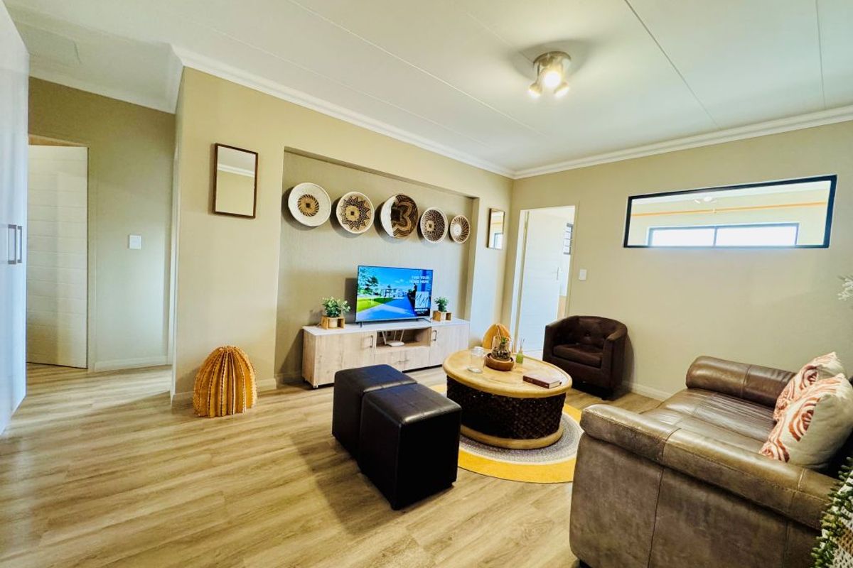 A well-maintained living room featuring laminate flooring, a recessed wall niche for media, and a horizontal clerestory window providing natural light.