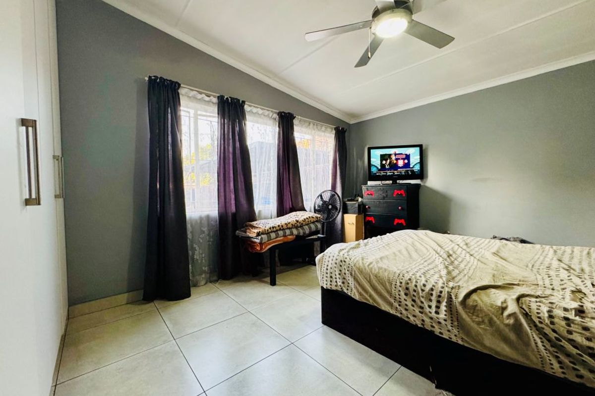 A bedroom featuring tiled flooring, a ceiling fan, and built-in wardrobe storage.