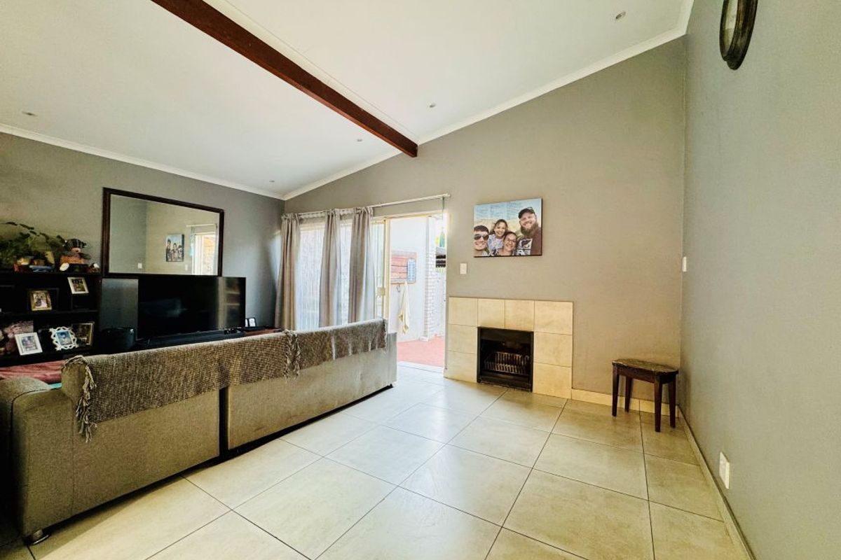 Spacious living room featuring tiled flooring, a built-in fireplace, exposed ceiling beam, and direct access to an outdoor patio area.