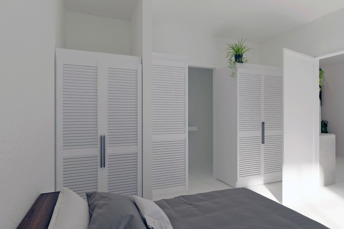 A bright bedroom featuring white built-in cupboards with louvered doors and clean tiled flooring.