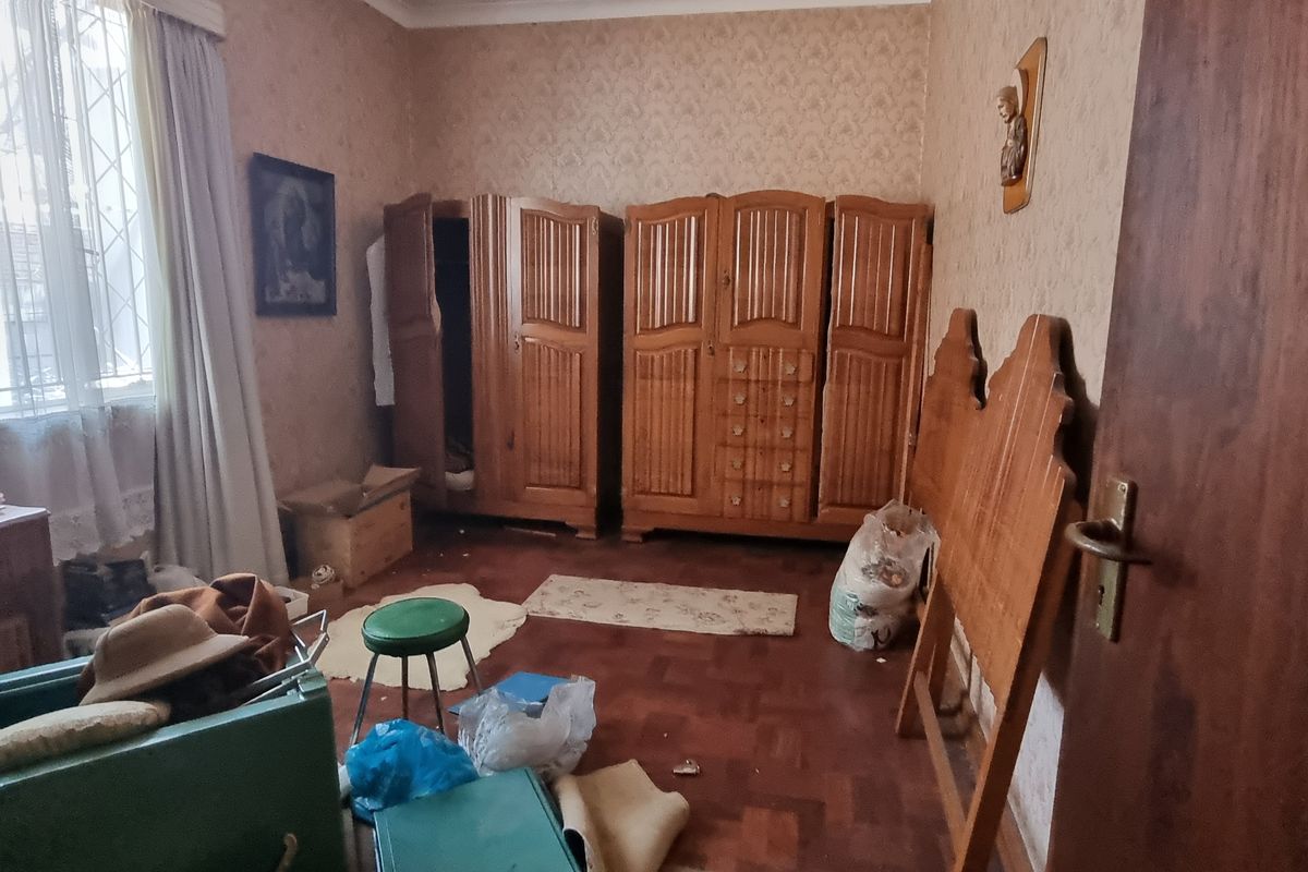 A bedroom featuring parquet flooring, security bars on the window, and traditional coving, currently requiring cosmetic updates and renovation.