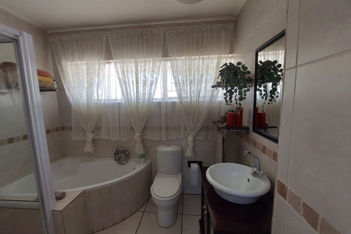 A functional bathroom featuring a corner bathtub, separate shower enclosure, vessel sink vanity, and neutral wall tiling.