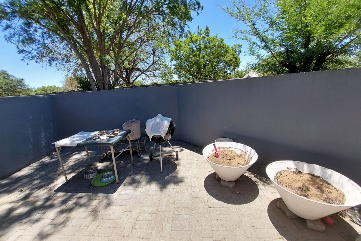 A private rear patio area featuring paved flooring and a solid perimeter boundary wall, offering a blank canvas for outdoor living and landscaping.