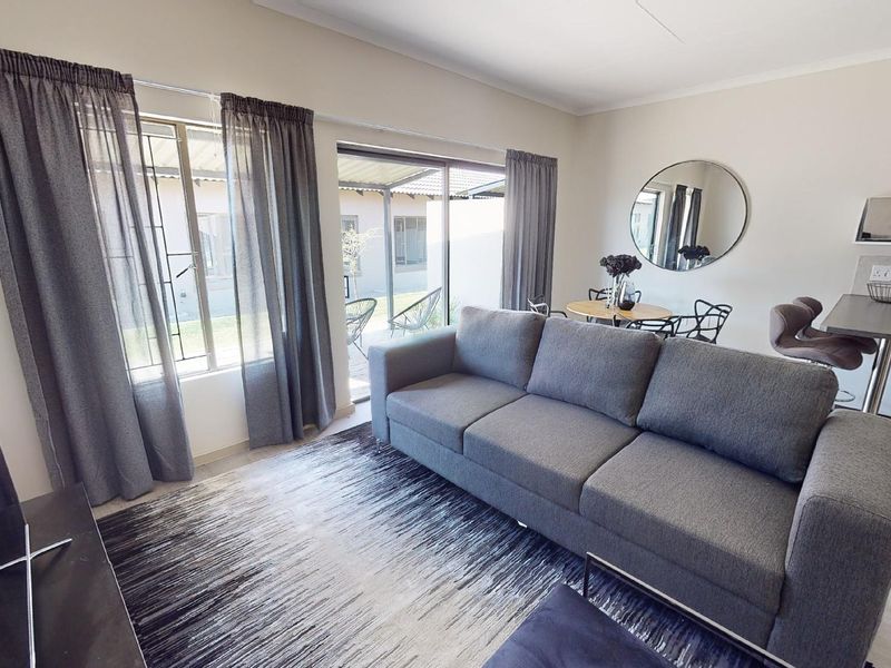 Open-plan living area featuring laminate flooring, sliding glass doors to the patio, and a built-in breakfast bar.