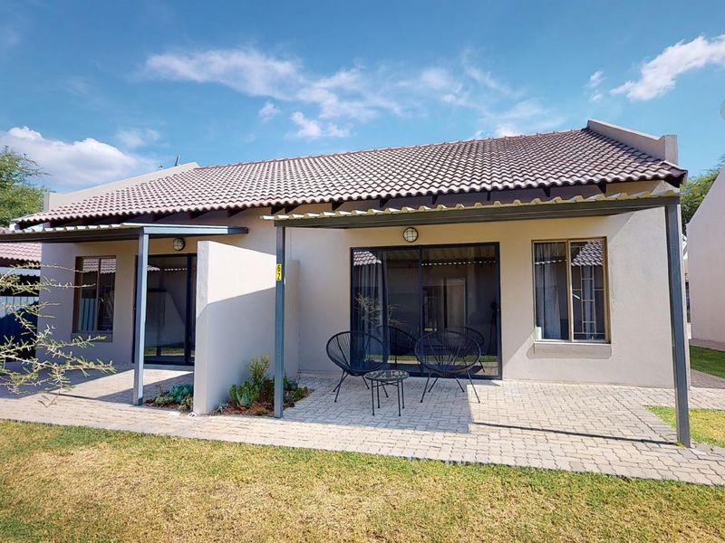 Rear view of the property featuring a paved patio area, metal pergola, and sliding glass doors leading into the home.