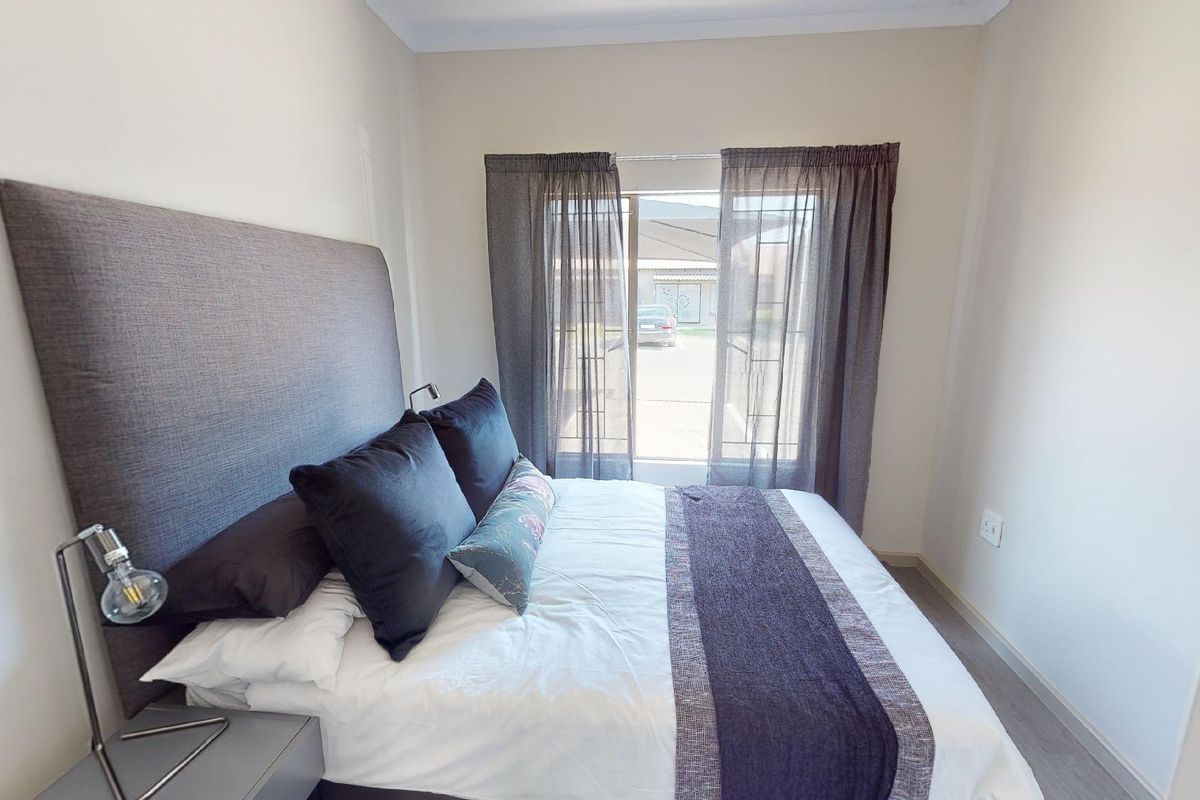 A well-maintained bedroom featuring neutral walls, coving, and a sliding glass door providing natural light and access to the exterior.