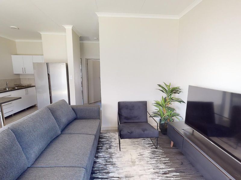 An open-plan living area featuring a modern kitchen with sleek cabinetry and a comfortable lounge space, creating a functional and cohesive living environment.