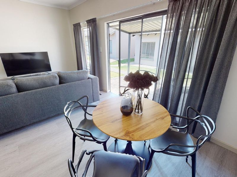 A bright living area featuring laminate flooring and large sliding glass doors that provide direct access to the outdoor patio and garden area.