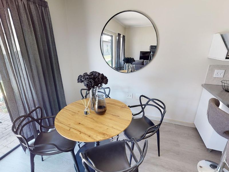An open-plan living area featuring light laminate flooring, a breakfast bar, and a sliding glass door providing access to the exterior.