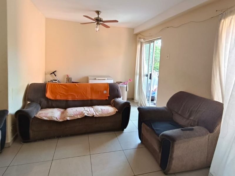 A living room featuring tiled flooring, a ceiling fan, and a sliding glass door providing access to the exterior.