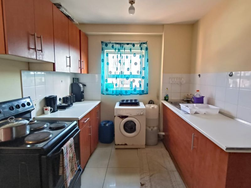 A functional galley-style kitchen featuring laminate cabinetry, tiled backsplash, and tiled flooring, offering a practical layout for daily meal preparation.