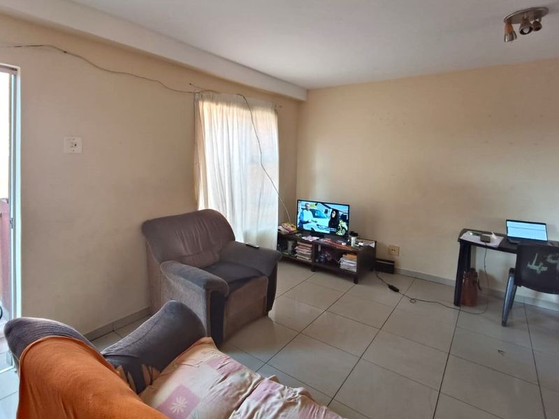A living room featuring tiled flooring and a sliding glass door, providing access to an outdoor area.