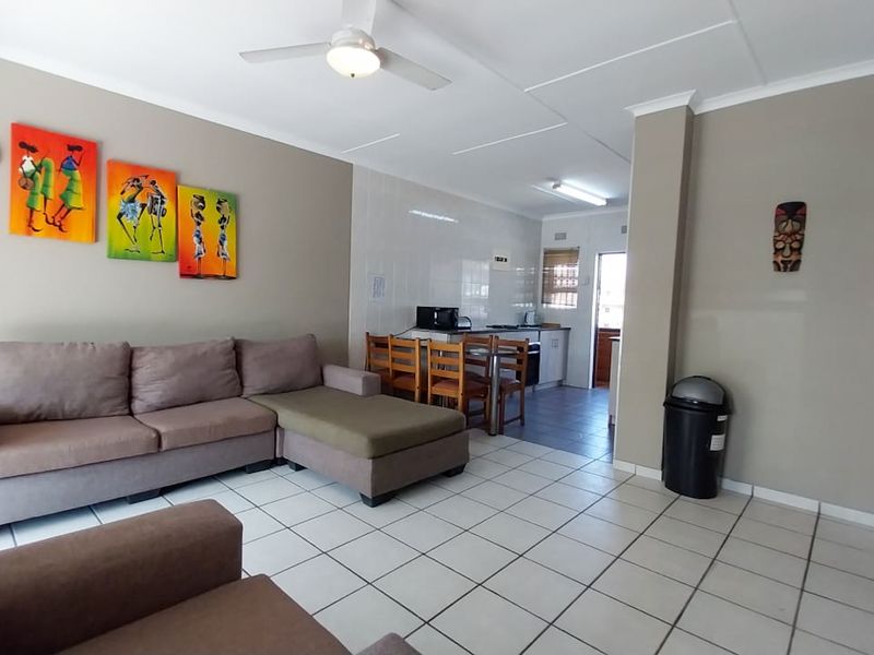 Open-plan living and kitchen area featuring tiled flooring, neutral wall tones, and a functional kitchen layout with built-in cabinetry.