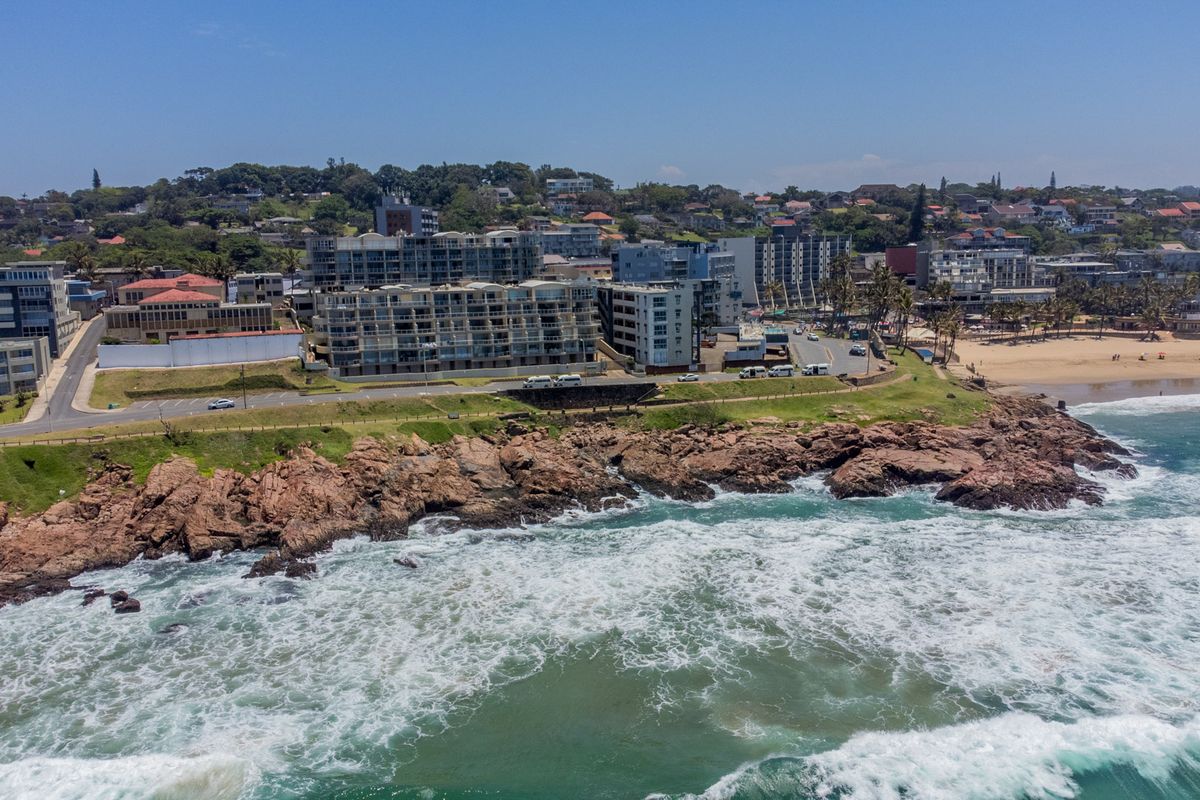Aerial view of the coastal apartment complex situated along the rocky shoreline and beach.