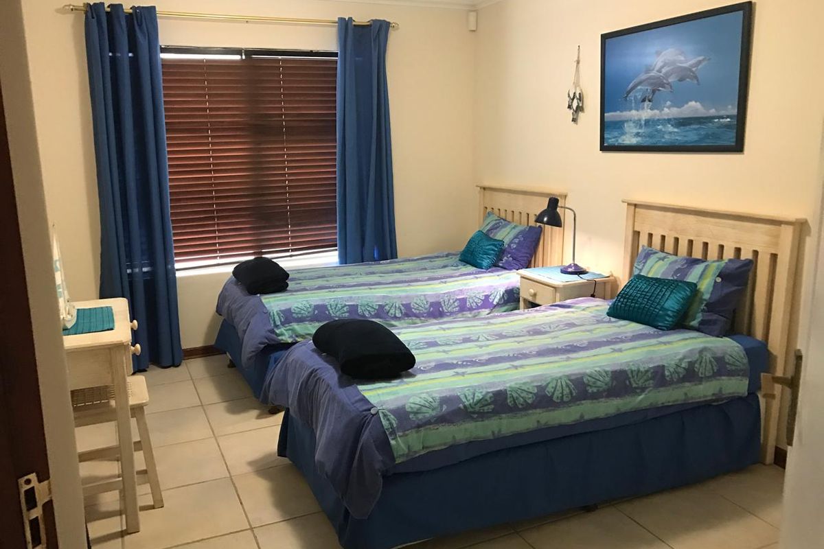 A bedroom featuring tiled flooring, wooden window blinds, and crown molding, providing a functional and comfortable living space.