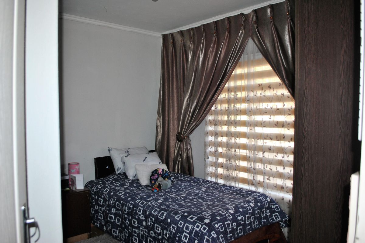 A bedroom featuring a built-in wardrobe and window treatments including curtains and blinds.