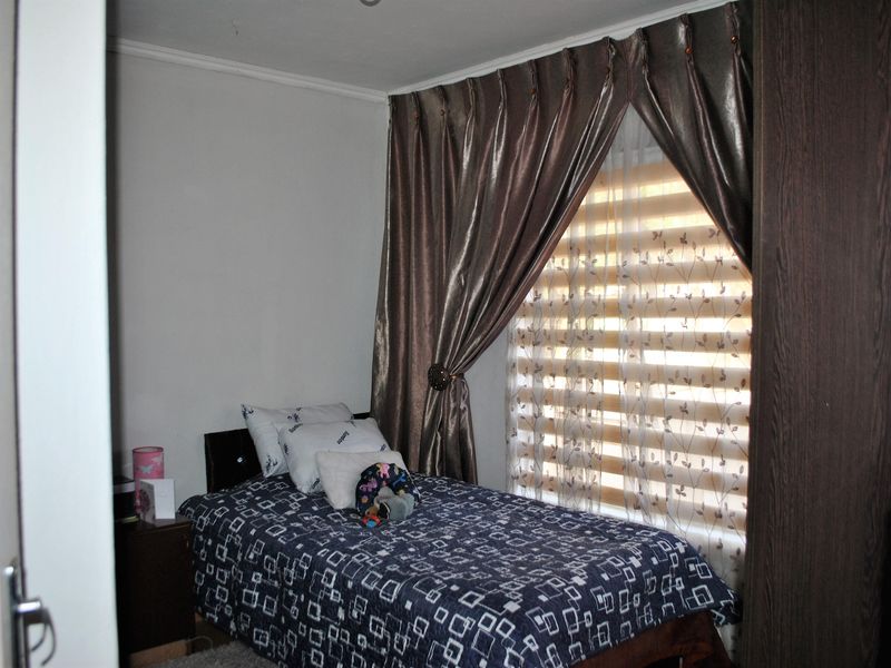 A bedroom featuring a built-in wardrobe and window treatments including curtains and blinds.