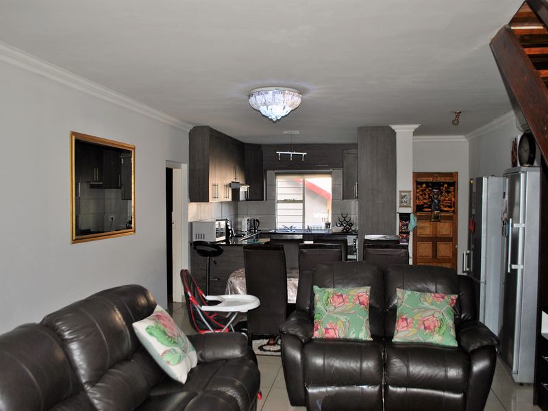 Open-plan living area featuring a kitchen with built-in cabinetry and tiled flooring, seamlessly connected to the main living space.