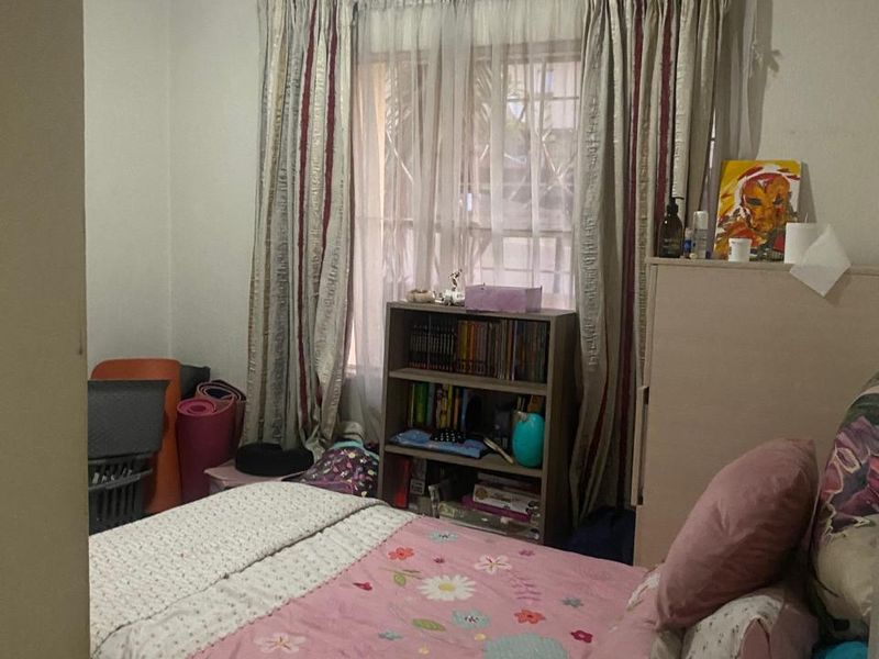 A standard bedroom featuring a window with curtain tracks and ceiling cornice detailing.