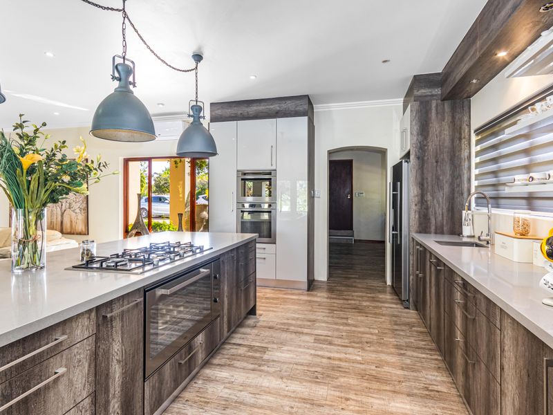Modern kitchen featuring a large central island with a built-in gas hob and oven, complemented by sleek cabinetry and high-quality stone countertops.