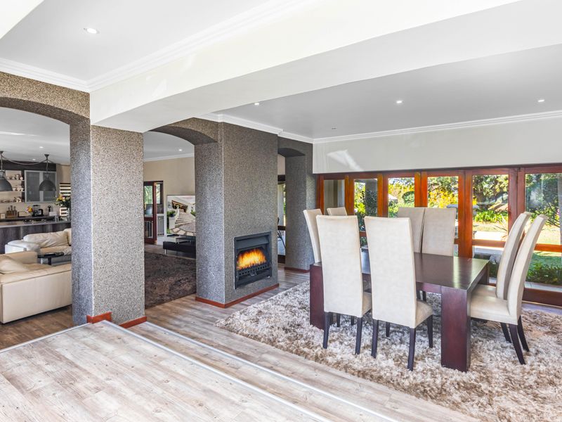 Spacious open-plan living and dining area featuring a built-in fireplace, recessed lighting, and large wooden framed glass doors leading to the garden.