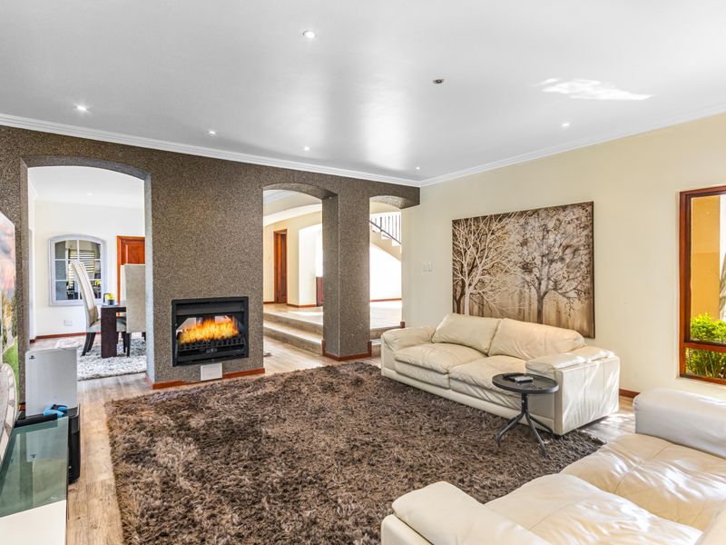 Spacious living room featuring a built-in fireplace with a textured feature wall, recessed downlighting, and arched transitions to adjacent living areas.