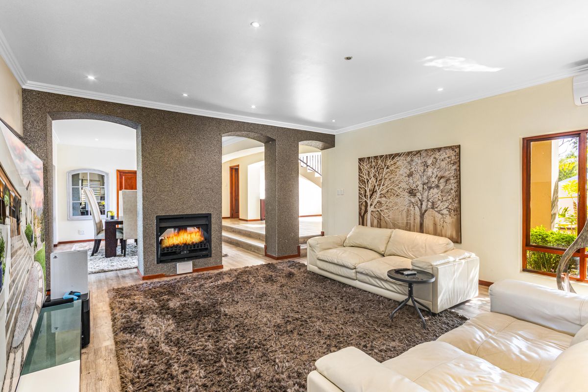 Spacious living room featuring a built-in fireplace with a textured feature wall, recessed downlighting, and arched transitions to adjacent living areas.