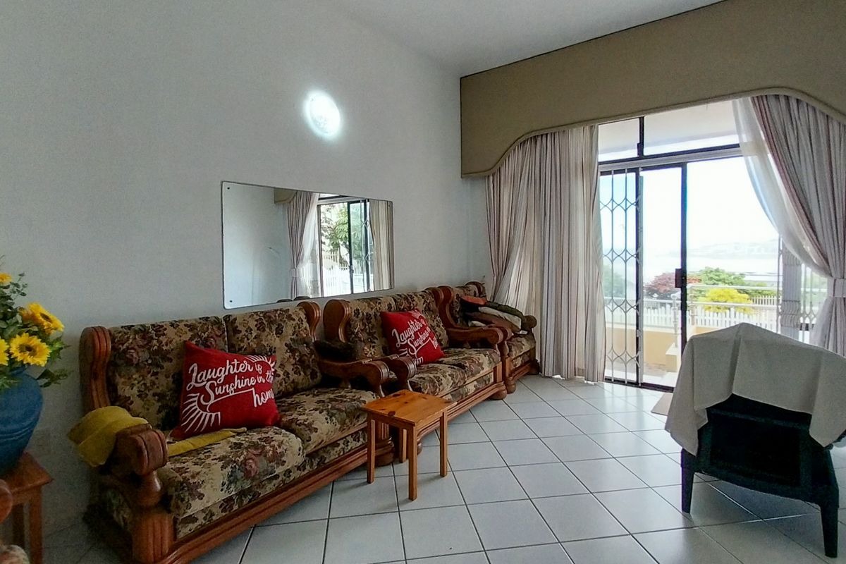 A living room featuring tiled flooring, a large sliding glass door with security gate, and access to an outdoor area.