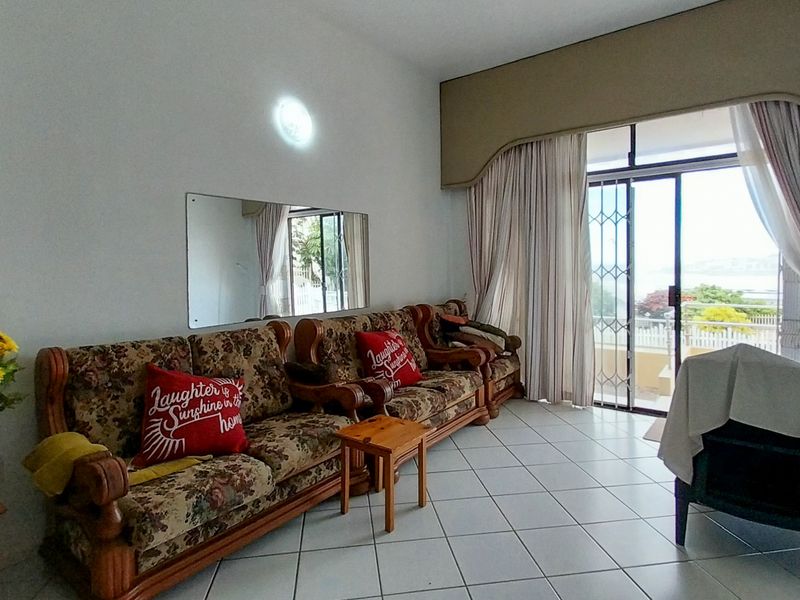 A living room featuring tiled flooring, a large sliding glass door with security gate, and access to an outdoor area.