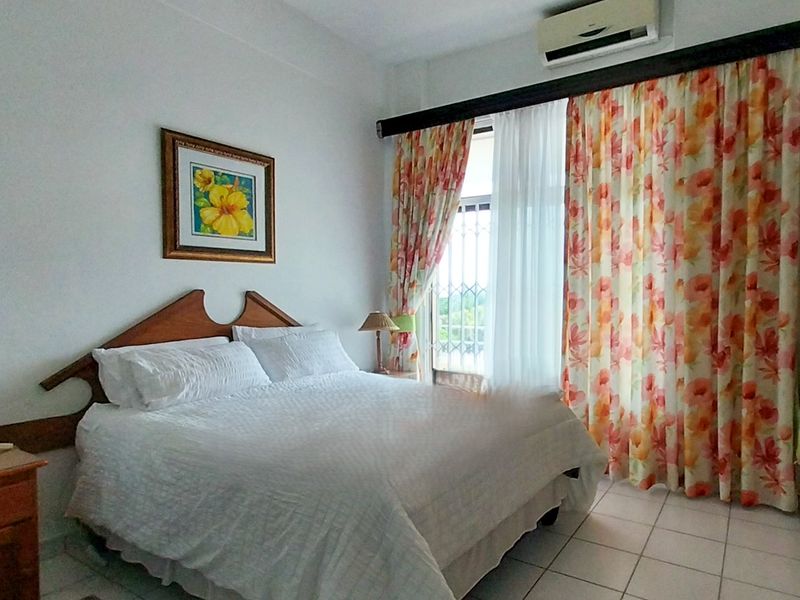A functional bedroom featuring tiled flooring, a built-in wardrobe, and a wall-mounted air conditioning unit with access to a balcony.