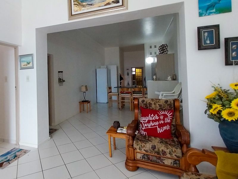 Open plan living and kitchen area featuring white tiled flooring and a spacious layout connecting the main living space to the kitchen.