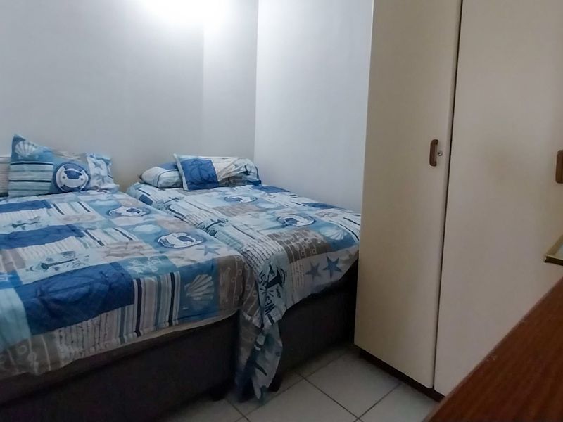 A functional bedroom featuring tiled flooring and a built-in wardrobe, providing essential storage space.