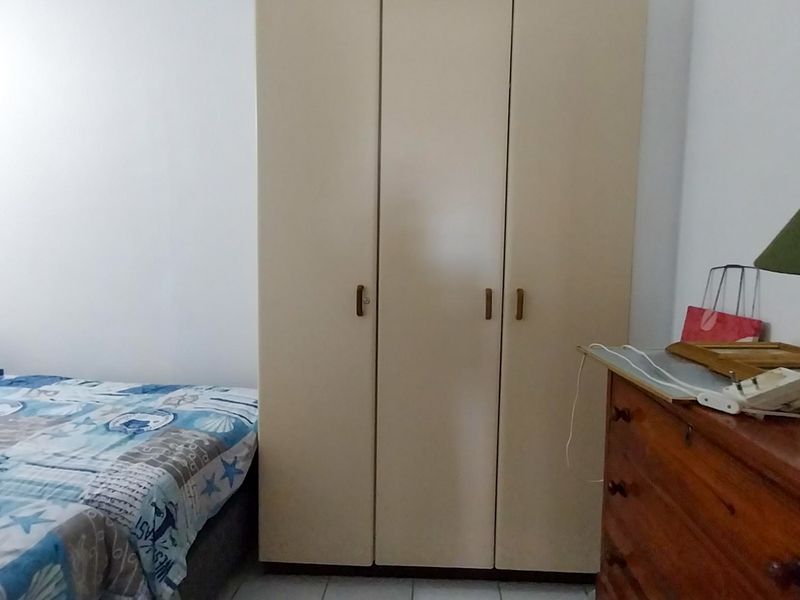 A bedroom featuring a neutral-toned built-in wardrobe with three doors, providing functional storage space.