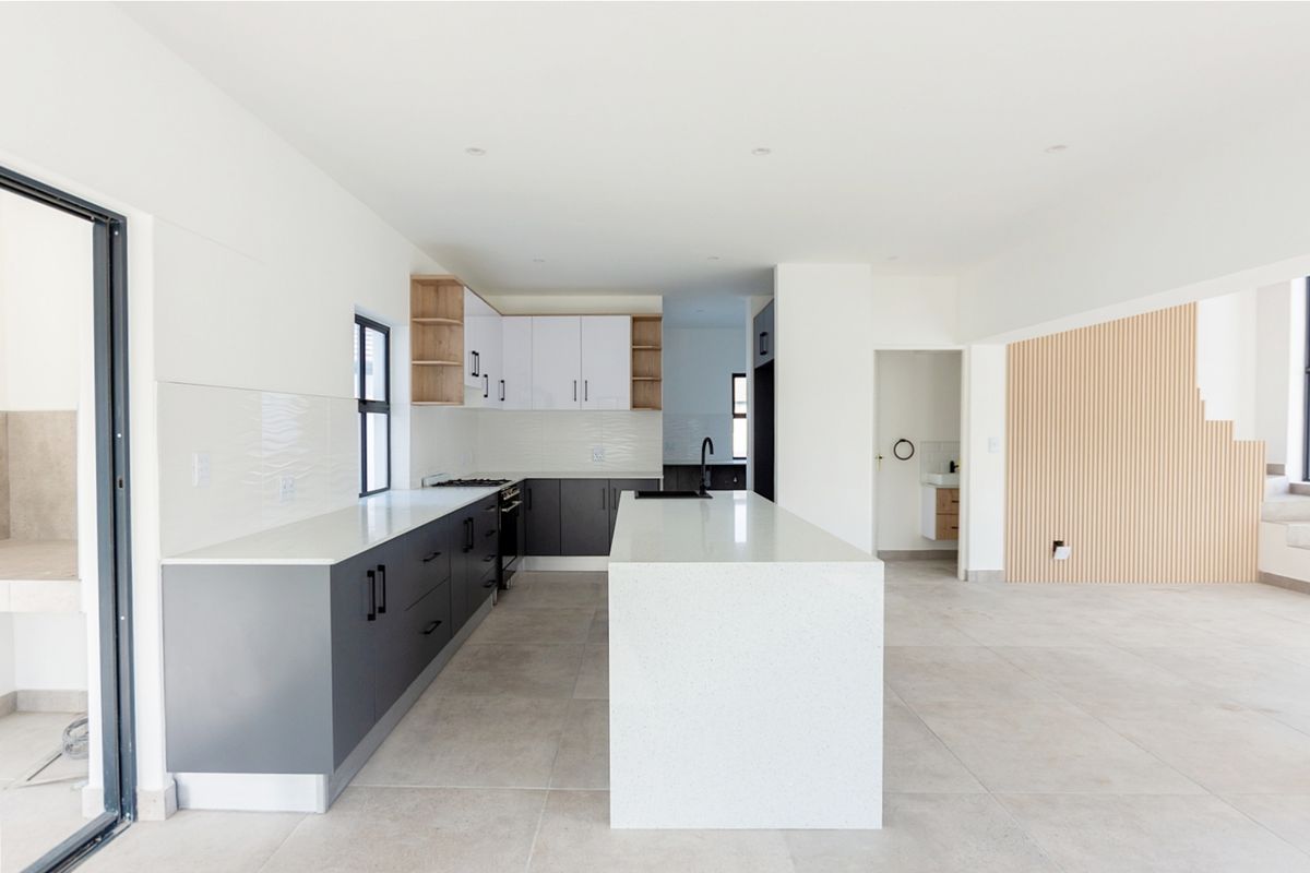 Modern open-plan kitchen featuring a central island, quartz countertops, two-tone cabinetry, and stylish slatted wood wall accents in a bright, contemporary space.