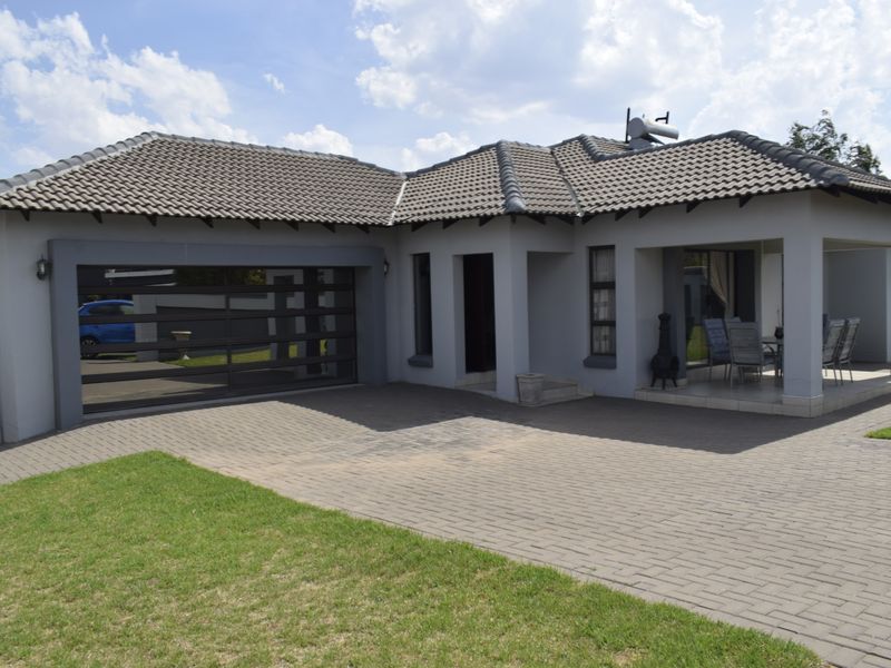 Front view of a modern single-story house featuring a paved driveway, integrated garage, and a covered patio area.