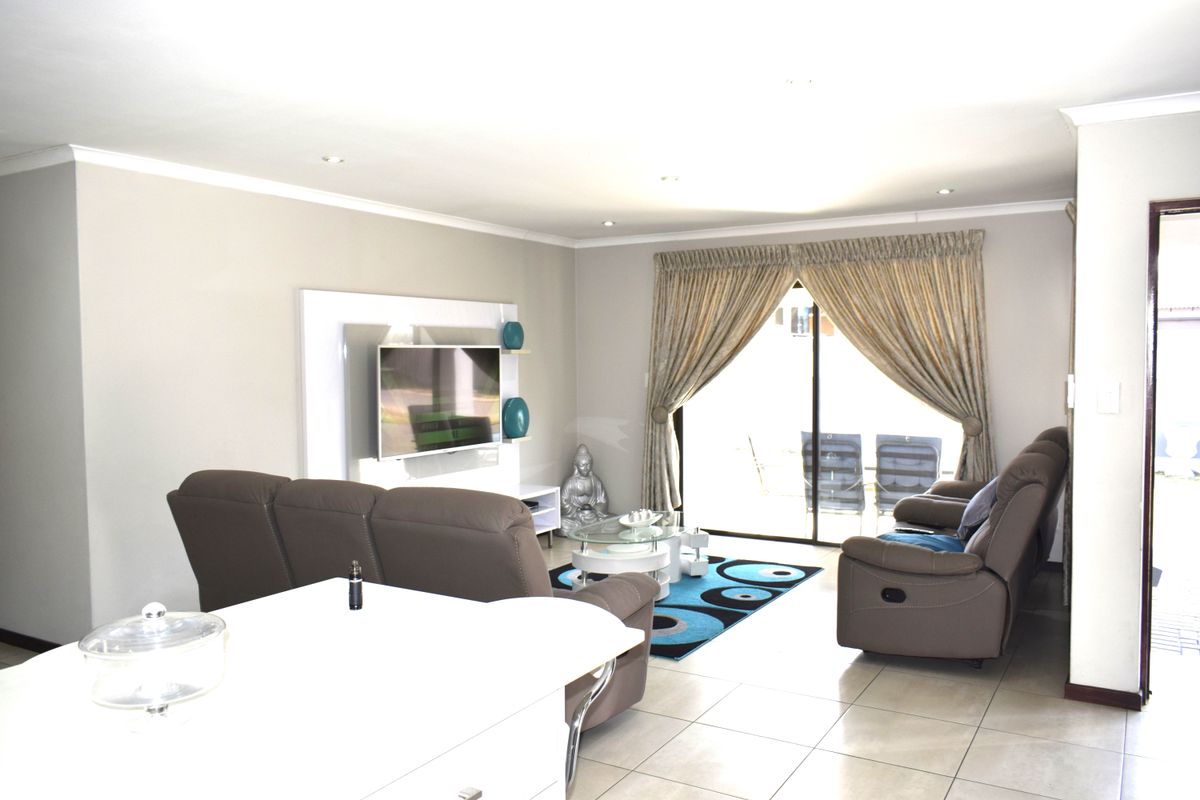 A bright living room featuring tiled flooring, recessed downlights, and a sliding glass door providing access to the outdoor area.