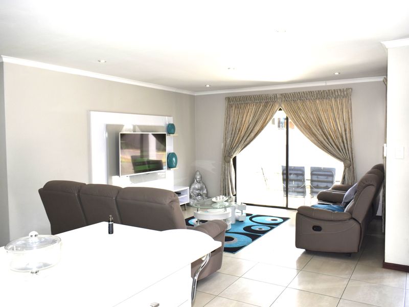 A bright living room featuring tiled flooring, recessed downlights, and a sliding glass door providing access to the outdoor area.