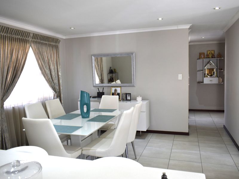A bright and well-maintained dining room featuring neutral tiled flooring, recessed downlighting, and coved cornicing, creating a clean and inviting space for meals.