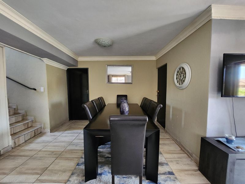 A dining room featuring tiled flooring, crown molding, and an adjacent staircase, providing a functional space for family meals and entertaining.