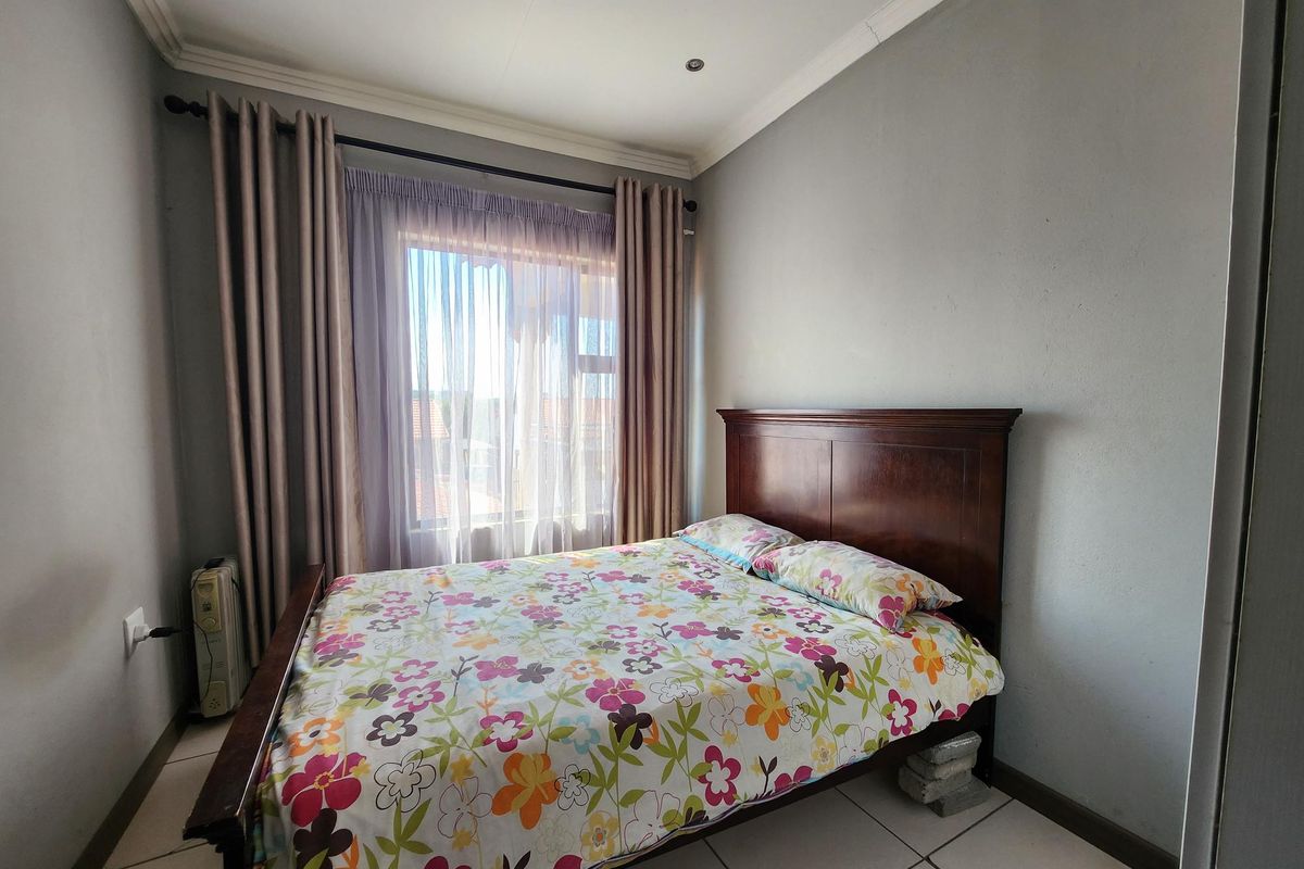 A functional bedroom featuring tiled flooring, coved ceilings, recessed lighting, and a built-in wardrobe, offering a neutral base for personalization.