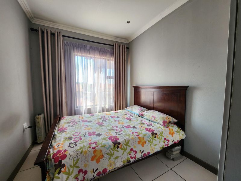 A functional bedroom featuring tiled flooring, coved ceilings, recessed lighting, and a built-in wardrobe, offering a neutral base for personalization.