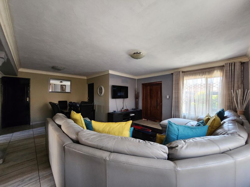 Spacious open-plan living area featuring tiled flooring, neutral wall tones, and direct access to the exterior through a sliding glass door.
