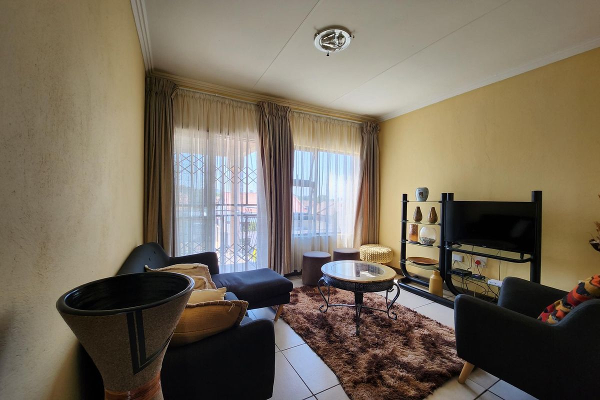 A living room featuring tiled flooring and a sliding glass door with security gate, providing access to an outdoor area.