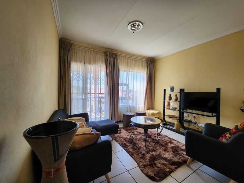 A living room featuring tiled flooring and a sliding glass door with security gate, providing access to an outdoor area.