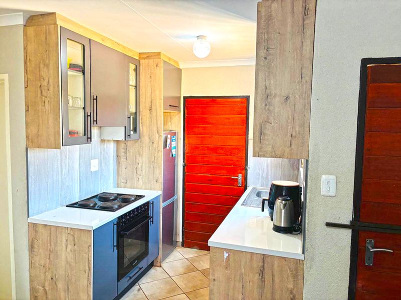 Compact kitchen featuring wood-look cabinetry, electric hob, built-in oven, and tiled flooring, providing a functional workspace.