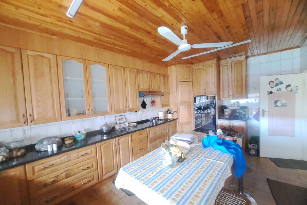 Spacious kitchen featuring extensive wooden cabinetry, granite countertops, a timber ceiling, and a ceiling fan, offering a warm and functional cooking environment.