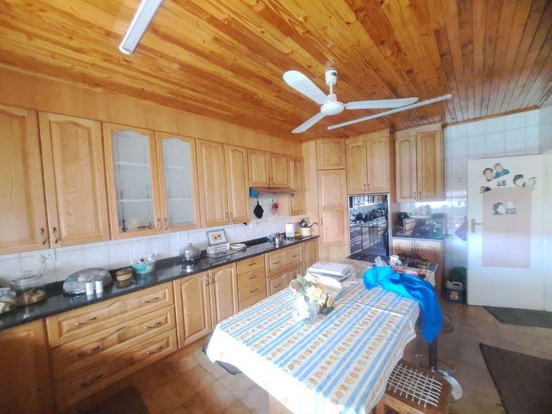Spacious kitchen featuring extensive wooden cabinetry, granite countertops, a timber ceiling, and a ceiling fan, offering a warm and functional cooking environment.