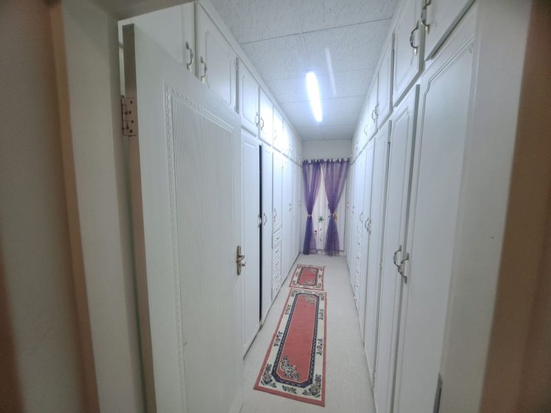 A narrow hallway featuring extensive floor-to-ceiling built-in cabinetry along both walls, providing ample storage space.