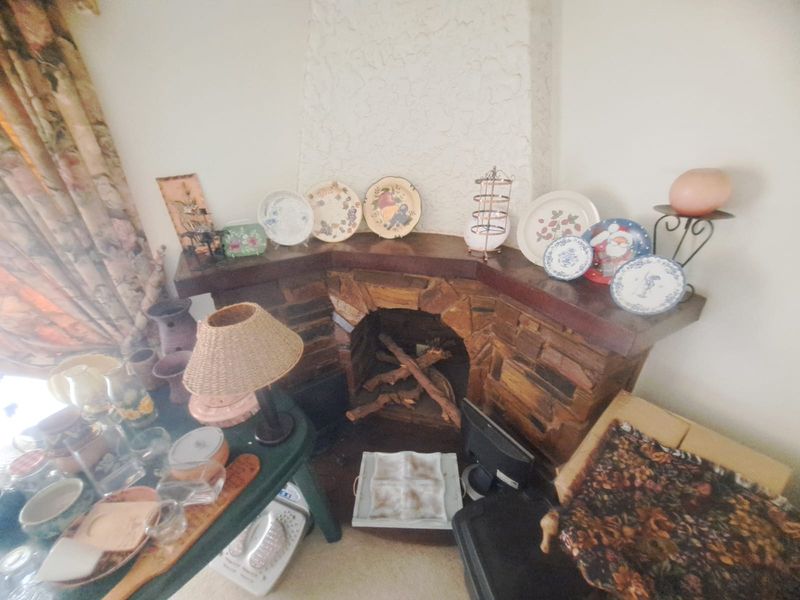 A corner fireplace featuring a rustic stone surround and a timber mantelpiece, serving as a focal point in the living area.