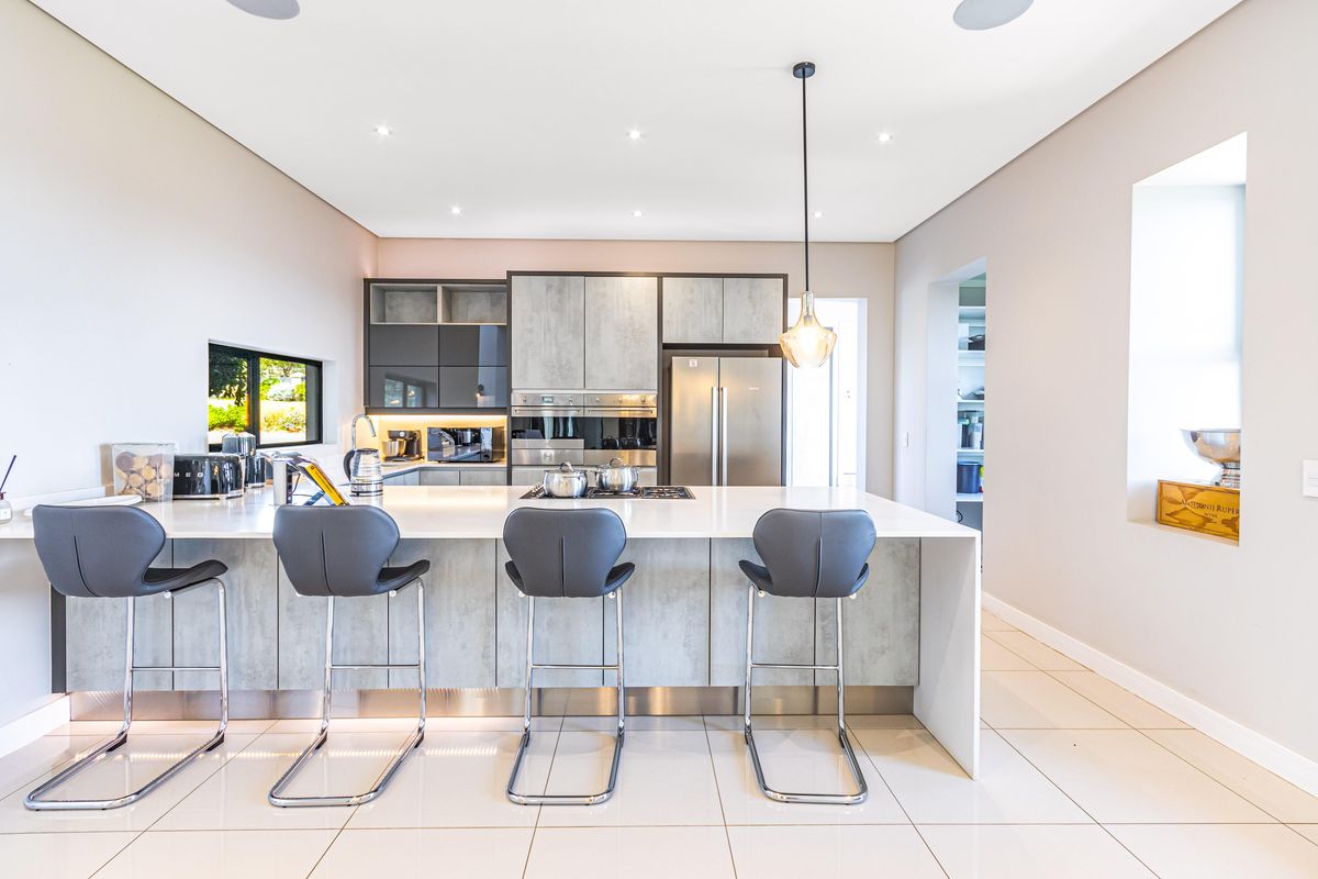 Modern kitchen featuring a large central island with stone countertop, integrated stainless steel appliances, sleek cabinetry, and recessed ceiling lighting.